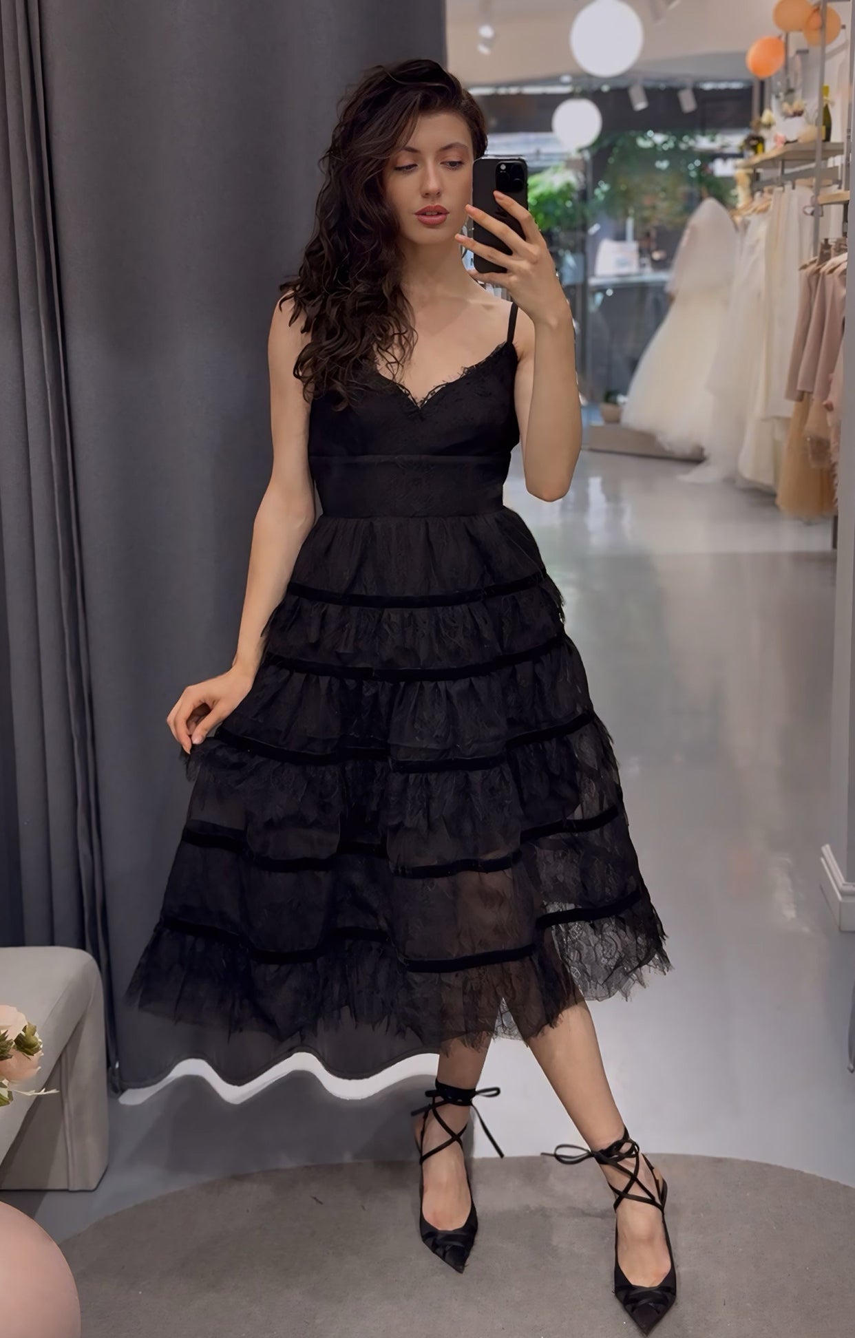 Официална рокля Gothic Grace LIZA KAIN София. Коктейлна рокля със средна дължина. Черна рокля, покрита с черна дантела. Триъгълно деколте с презрамки. Широк колан. Разкроена пола с множество волани, разделени от кадифена лента.