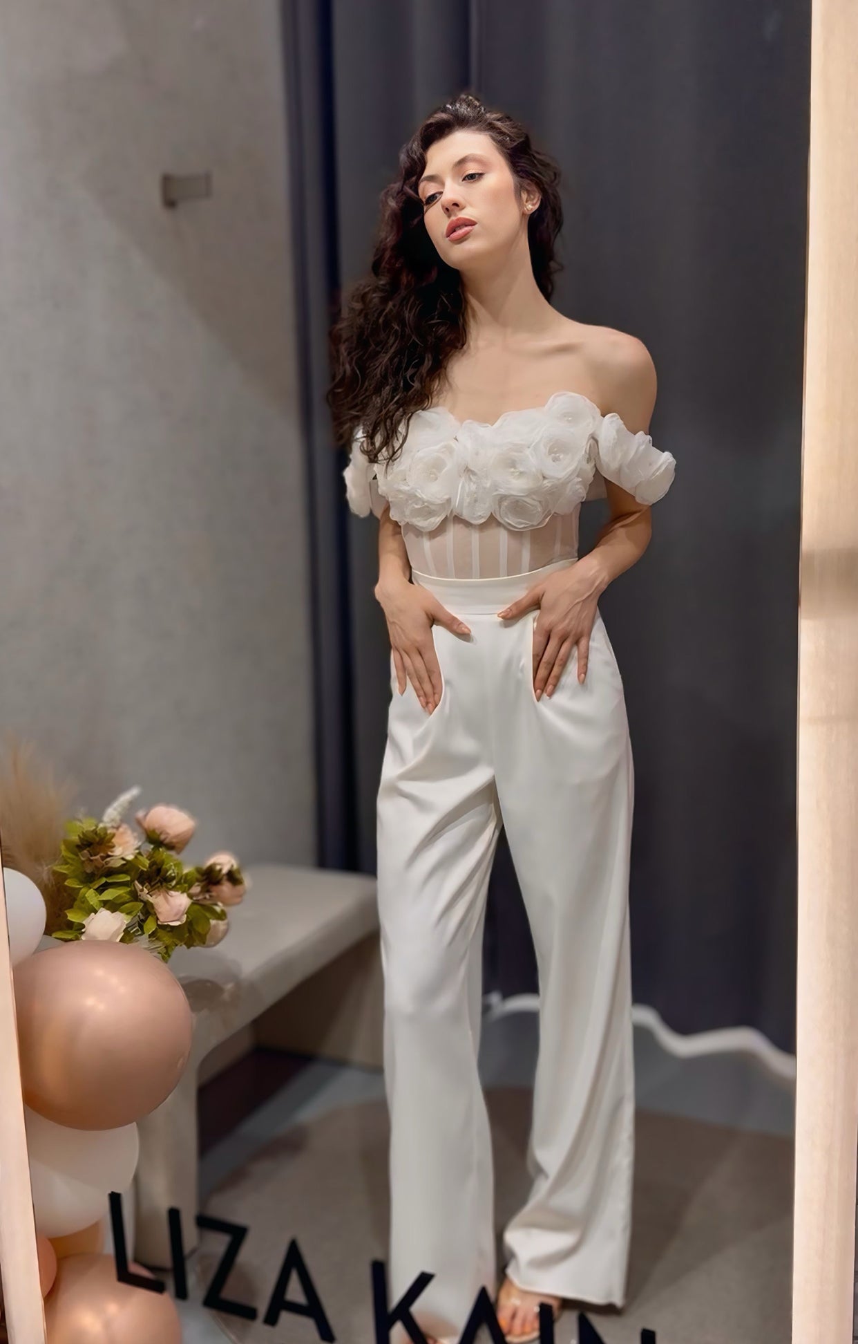 Официален комплект Enchanted Ivy LIZA KAIN София. Булчински комплект от бюстие с прозрачна основа и паднали презрамки. Апликации от цветя и перли.Бял сатенен панталон с висока талия, джобове и плохи. Прав панталон.