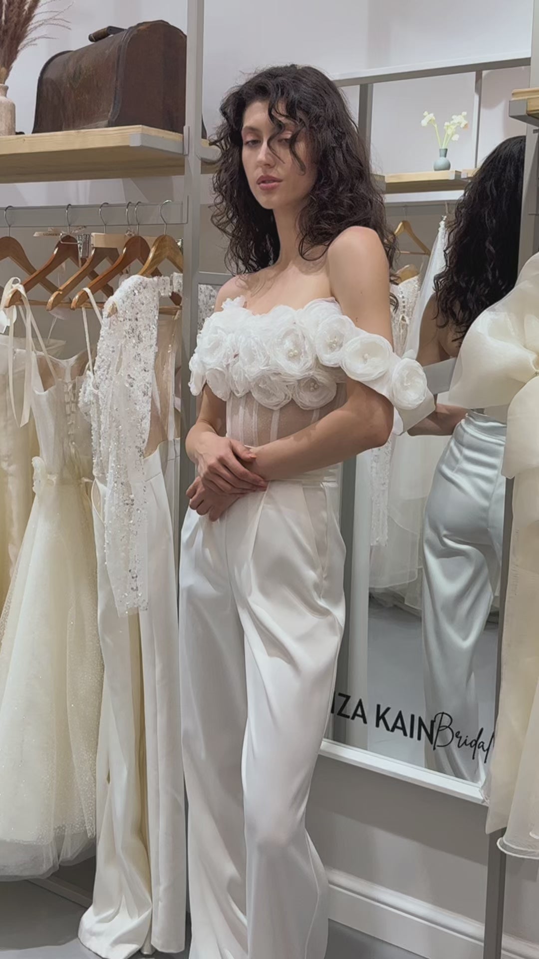 Официален сет Enchanted Ivy LIZA KAIN София. Булчински комплект от бюстие с паднали ръкави, прозрачна основа и апликации от цветя. Бял сатенен панталон с висока талия, джобове и плохи. Прав панталон.