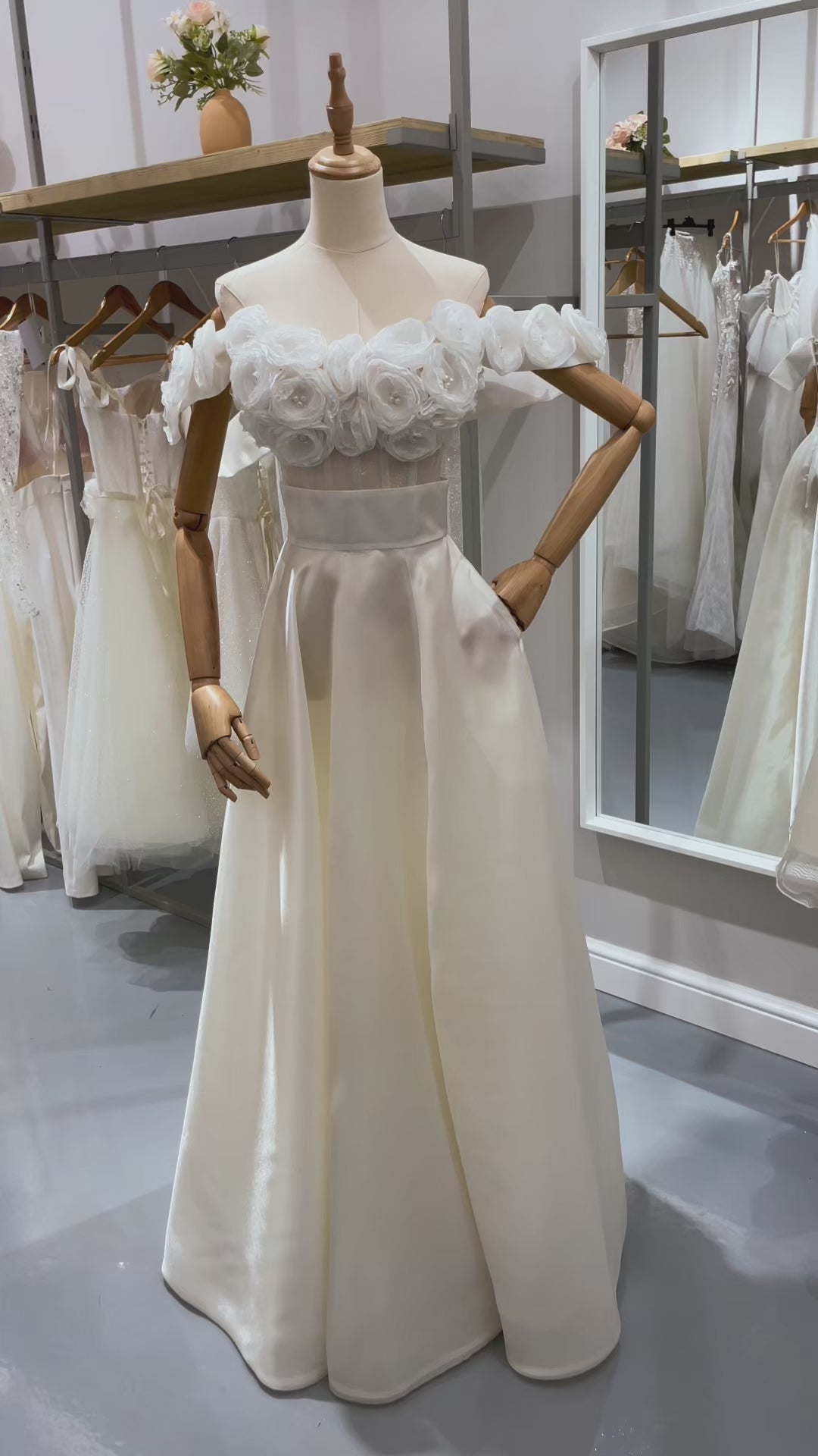 Дълга булчинска рокля Beatrice LIZA KAIN София. Бяла официална рокля от две части. Прозрачен корсет с апликации от цветя от органза и паднали презрамки. Клоширана пола от органза с широк колан, джобове и цепка.